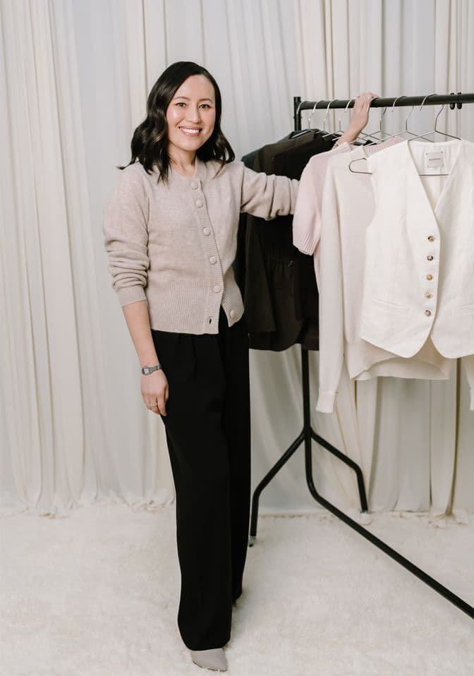Gulinka smiling beside a studio clothes rail
