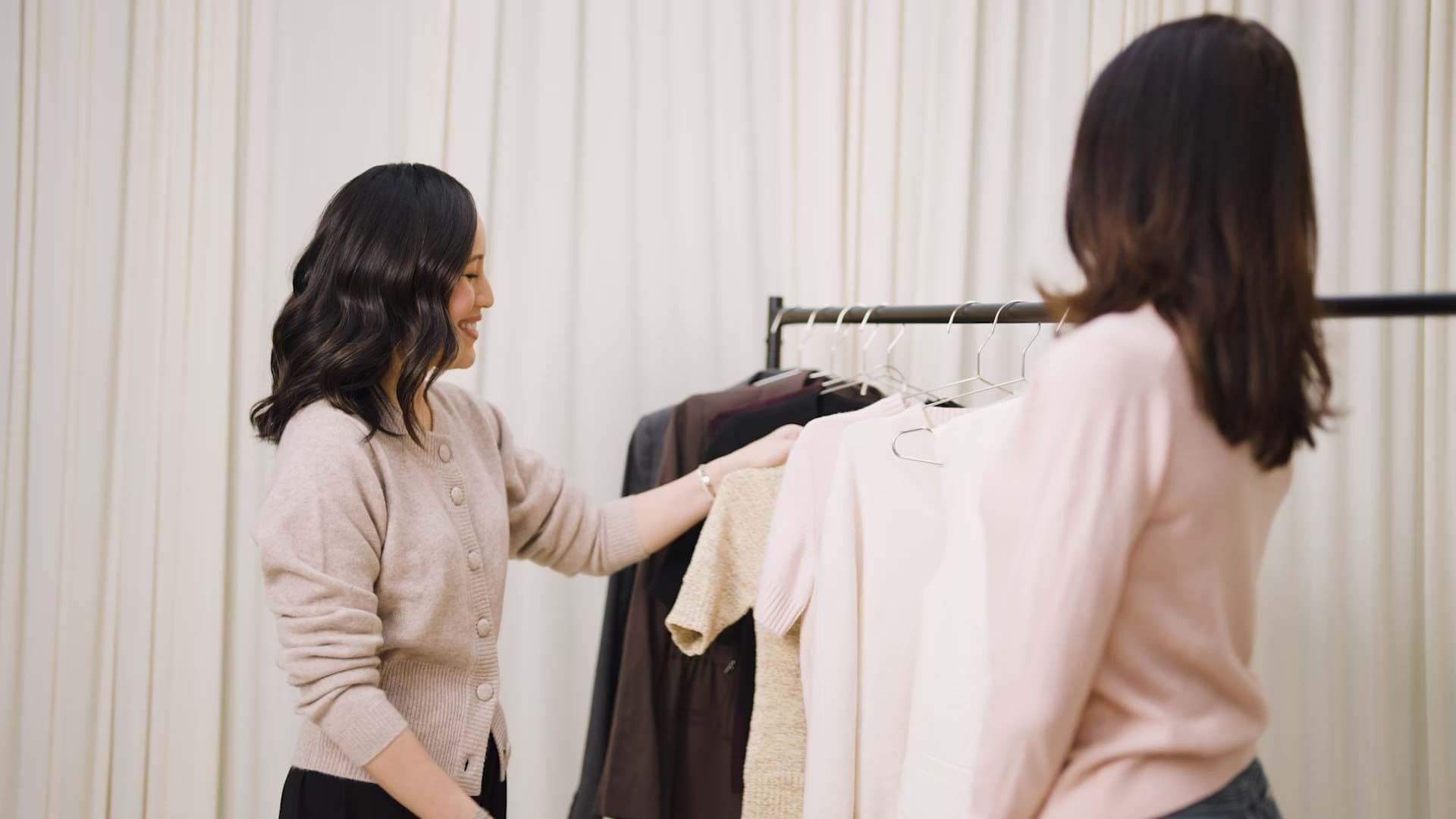 Gulinka browsing a lookbook beside a rack of neutral tailoring in her studio