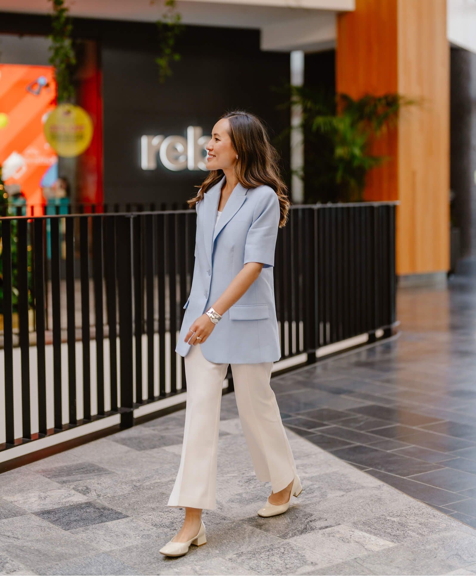 Gulinka smiling outside a store entrance in a pale blue blazer